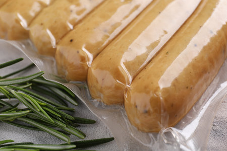 Vegan sausages and rosemary on white table, closeup