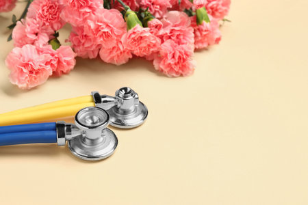 Stethoscopes and beautiful flowers on beige background, space for text. Happy Doctor's Dayの写真素材