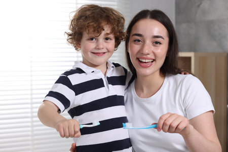 Mother and her son brushing teeth together in bathroomの写真素材