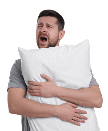 Sleepy man with pillow yawning on white background. Insomnia problemの写真素材