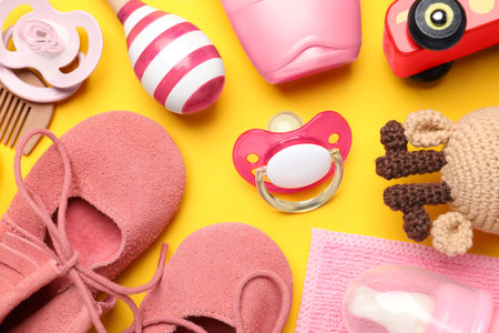 Flat lay composition with pacifiers and other baby stuff on yellow backgroundの写真素材