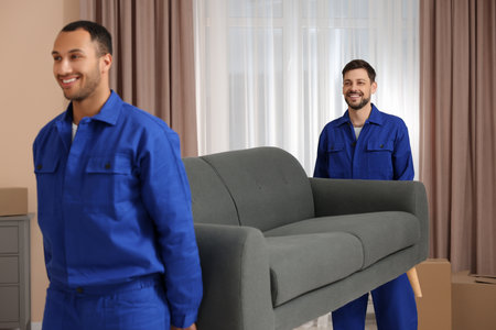 Male movers carrying sofa in new houseの写真素材