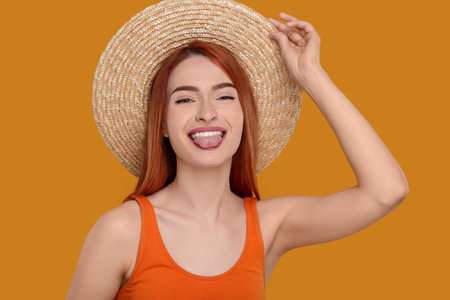 Happy woman showing her tongue on orange backgroundの写真素材