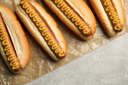 Fresh delicious hot dogs with mustard on light gray table, top viewの写真素材