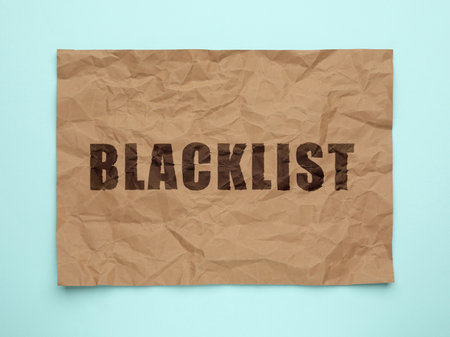 Crumpled paper with word Blacklist on light blue background, top viewの写真素材