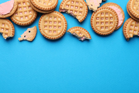Tasty sandwich cookies with cream on light blue background, flat lay. Space for textの写真素材