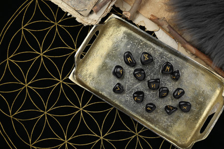 Many black rune stones on divination mat, flat lay. Space for text