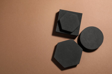 Black geometric figures on light brown background, flat lay and space for text. Stylish presentation...