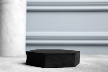 Black geometric figure on light gray table, closeup and space for text. Stylish presentation for productの写真素材