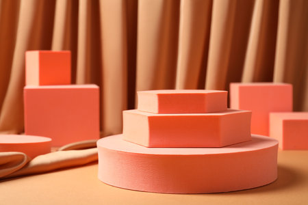 Geometric figures on table against light brown curtain. Stylish presentation for productの写真素材
