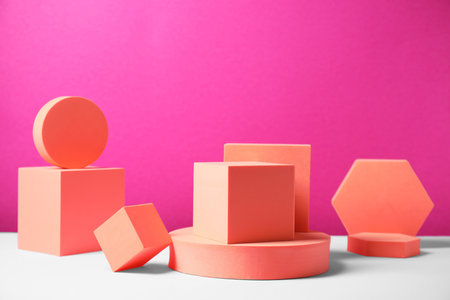 Geometric figures on white table against bright pink background. Stylish presentation for productの写真素材