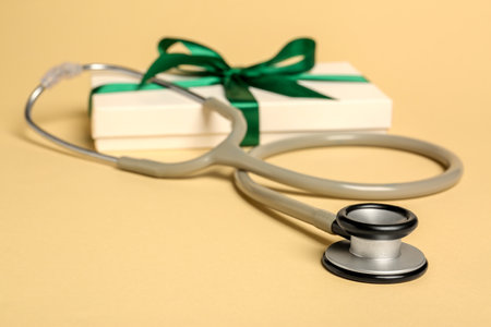 Stethoscope and gift box on beige background, closeup. Happy Doctor's Dayの写真素材