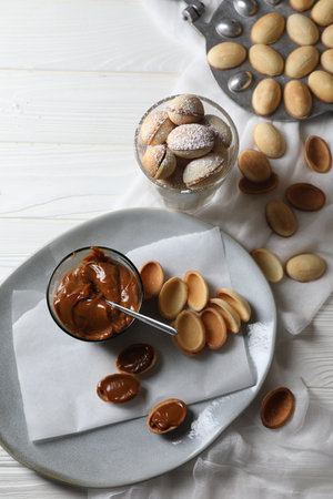 Delicious walnut shaped cookies with condensed milk on white wooden table, flat layの写真素材