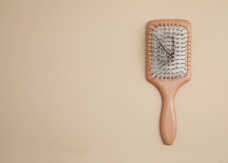 Wooden brush with lost hair on beige background, top view. Space for textの写真素材