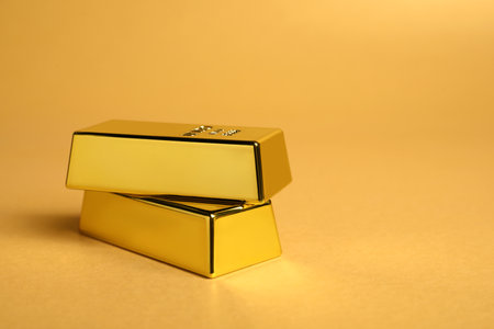 Shiny gold bars on pale orange background, closeup. Space for textの写真素材
