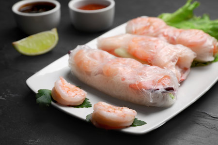 Delicious spring rolls with shrimps wrapped in rice paper served on black table, closeupの写真素材