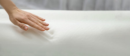 Woman touching memory foam pillow indoors, closeup. Banner design with space for textの写真素材