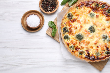 Delicious homemade quiche with salmon, broccoli, basil leaves and spices on wooden table, flat lay. Space for textの写真素材