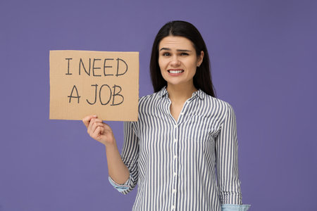 Unemployment problem. Unhappy woman holding sign with phrase I Need A Job on violet backgroundの写真素材