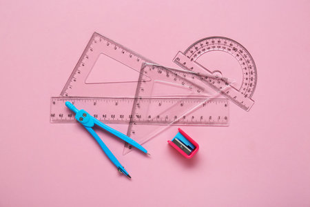 Different rulers, pencil sharpener and compass on pink background, flat layの写真素材
