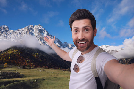 Smiling man with camera taking selfie in mountainsの写真素材