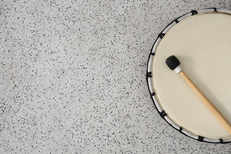 Drum and drumstick on gray table, top view with space for text. Percussion musical instrument