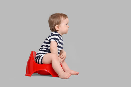 Little child sitting on baby potty against light gray background, space for textの写真素材
