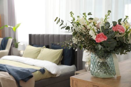 Large comfortable bed in room, focus on beautiful bouquet, space for text. Stylish interiorの写真素材