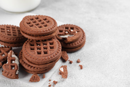 Tasty chocolate sandwich cookies with cream on light gray table, space for textの写真素材