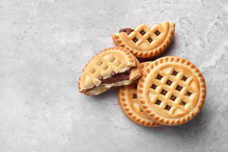 Tasty sandwich cookies with cream on gray table, flat lay. Space for text