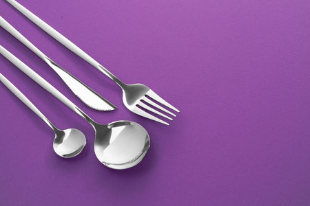 Fork, knife and spoons on purple background, flat lay with space for text. Stylish cutlery setの写真素材