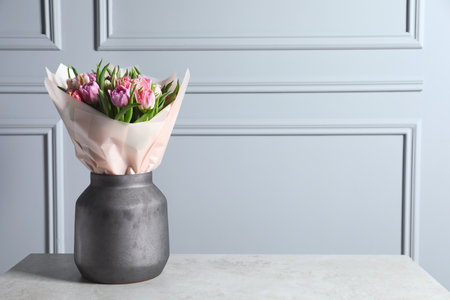 Vase with bouquet of beautiful tulips on gray table. Space for textの写真素材