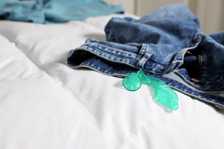 Unrolled condom and jeans on bed. Safe sexの写真素材