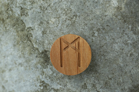 Wooden rune Mannaz on stone outdoors, closeupの写真素材