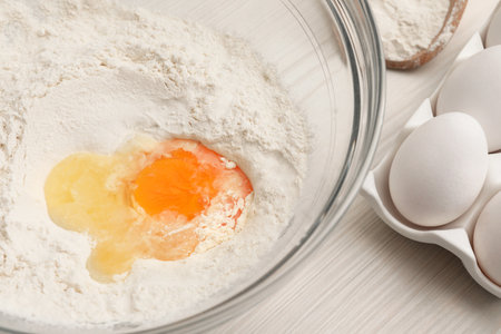 Bowl with flour and egg on white wooden table, closeupの写真素材