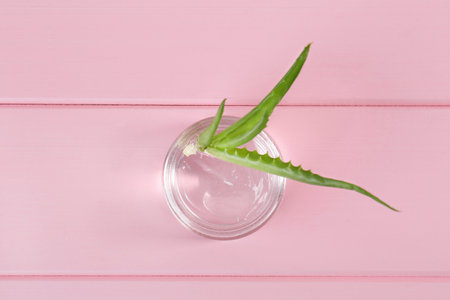 Jar of natural gel and aloe vera leaves on pink wooden table, top viewの写真素材