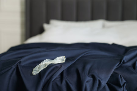 Unrolled condom on bed in bedroom. Safe sexの写真素材
