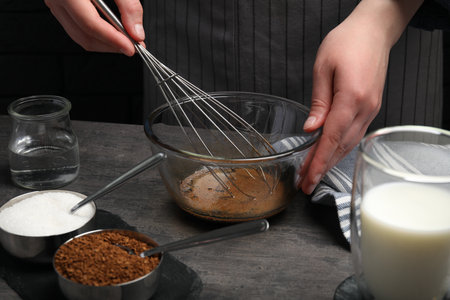 Woman whipping cream for dalgona coffee at gray table, closeup