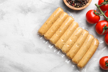 Vegan sausages and products on white marble table, flat lay. Space for text