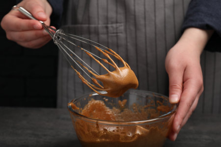Woman whipping coffee cream at gray table, closeup