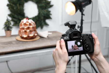 Food photography. Woman with professional camera taking photo of Pandoro cake, Christmas wreath and...