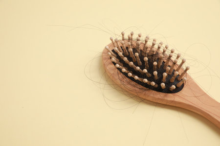 Wooden brush with lost hair on beige background, closeup. Space for textの写真素材