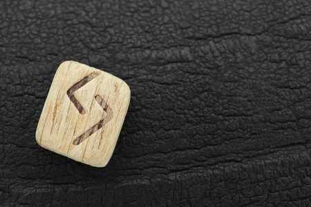 Wooden rune Jera on black textured background, top view. Space for textの写真素材