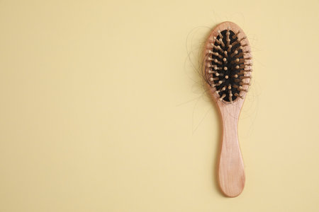 Wooden brush with lost hair on beige background, top view. Space for textの写真素材