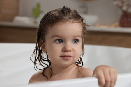 Cute little girl washing hair with shampoo in bathroomの写真素材