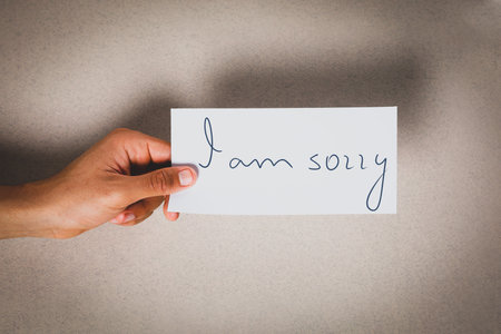 Apology. Man holding card with phrase I Am Sorry on gray background