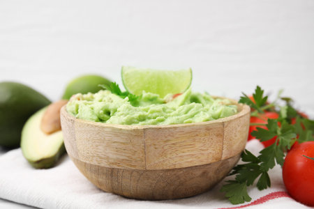 Bowl of delicious guacamole and ingredients on white table, closeupの写真素材