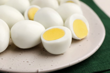 Many peeled hard boiled quail eggs on plate, closeup