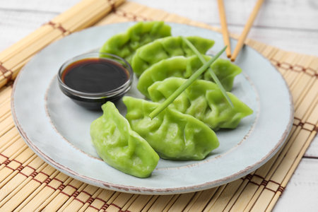 Delicious green dumplings (gyozas) and soy sauce on white table, closeupの写真素材