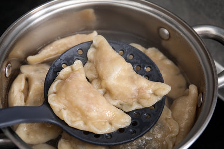 Boiling delicious dumplings (varenyky) on skimmer over pot, closeupの写真素材
